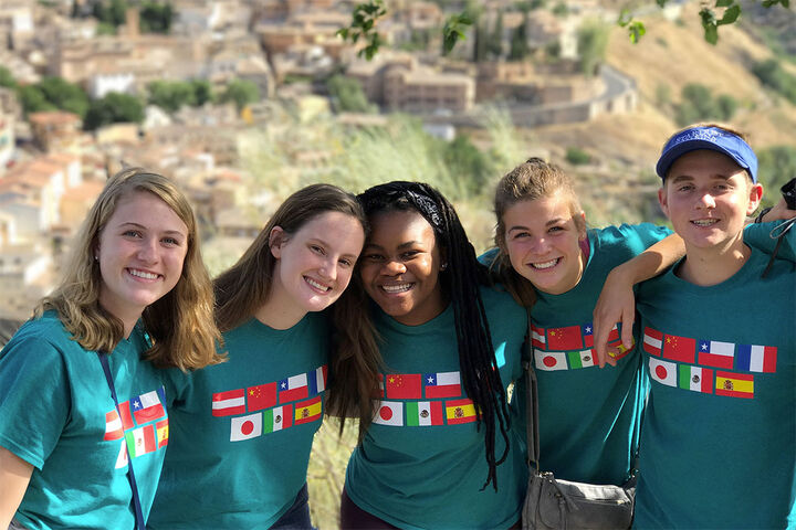 A small group of students wearing matching tee shirts showing various flags from different countries.